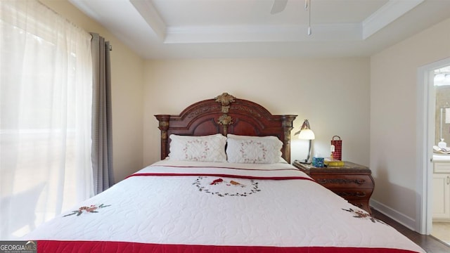 bedroom featuring ceiling fan, connected bathroom, and a tray ceiling