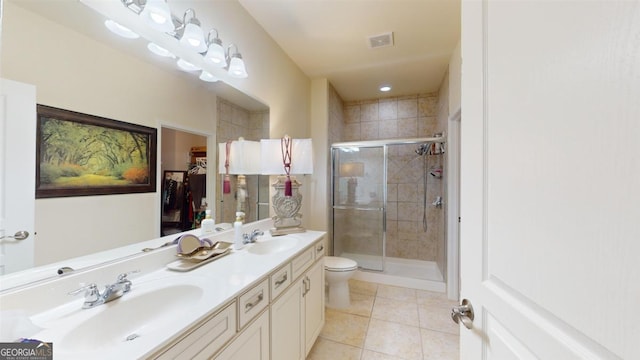 bathroom with toilet, vanity, a shower with door, and tile patterned floors