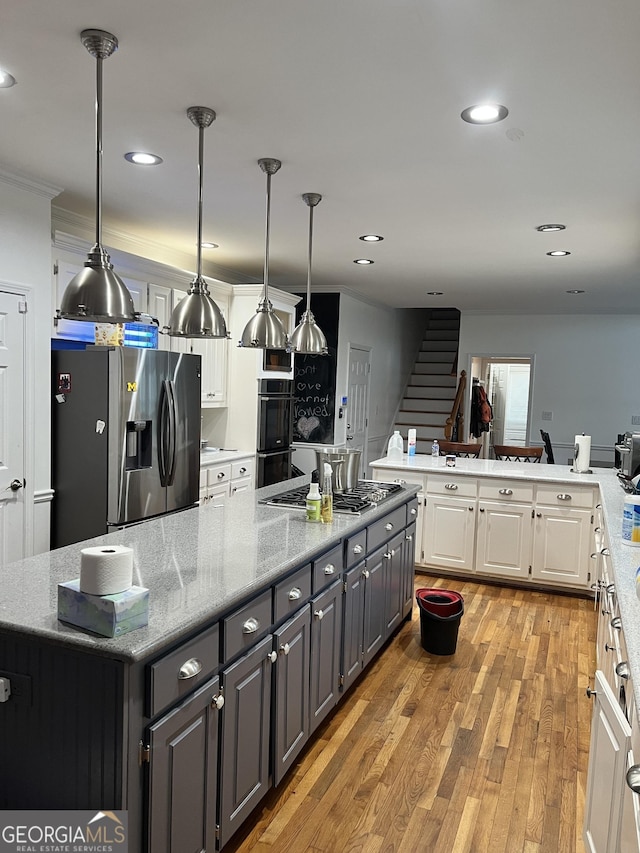 kitchen with a center island, light hardwood / wood-style flooring, light stone countertops, appliances with stainless steel finishes, and white cabinets