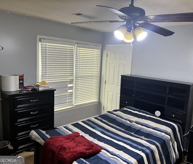 bedroom with ceiling fan and a textured ceiling