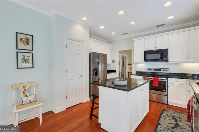 kitchen featuring white cabinetry, stainless steel appliances, tasteful backsplash, dark wood-type flooring, and a center island