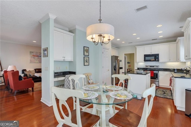 dining room with sink, dark hardwood / wood-style flooring, crown molding, and a chandelier