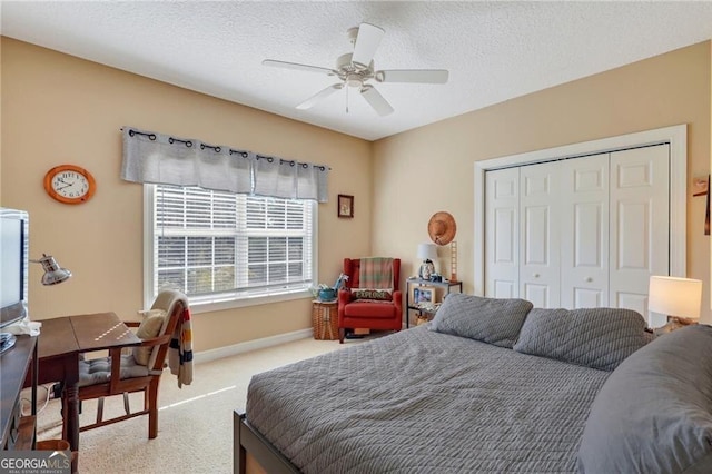 bedroom with a textured ceiling, ceiling fan, carpet flooring, and a closet