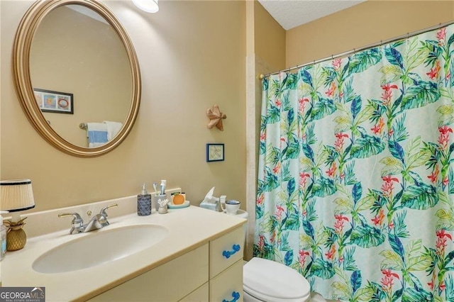 bathroom with toilet, vanity, and walk in shower