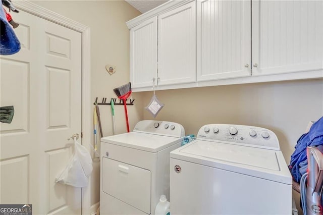 clothes washing area with cabinets and separate washer and dryer