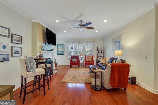 living room featuring ceiling fan, ornamental molding, and hardwood / wood-style flooring