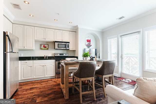 kitchen with stainless steel appliances, dark hardwood / wood-style flooring, white cabinetry, and ornamental molding