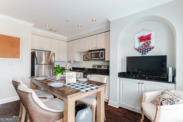 kitchen with white cabinets, appliances with stainless steel finishes, dark hardwood / wood-style floors, and crown molding