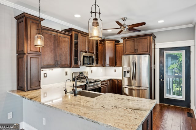 kitchen with ornamental molding, appliances with stainless steel finishes, kitchen peninsula, pendant lighting, and light stone countertops