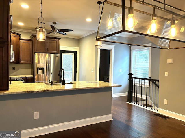 kitchen featuring crown molding, stainless steel fridge, hanging light fixtures, dark hardwood / wood-style floors, and light stone counters