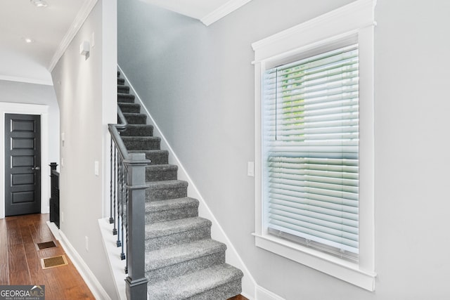 stairway with ornamental molding and hardwood / wood-style floors