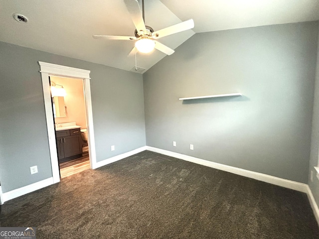 unfurnished bedroom featuring ceiling fan, vaulted ceiling, ensuite bath, and dark colored carpet