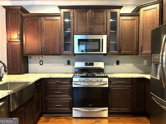 kitchen featuring appliances with stainless steel finishes, dark hardwood / wood-style flooring, light stone countertops, and sink