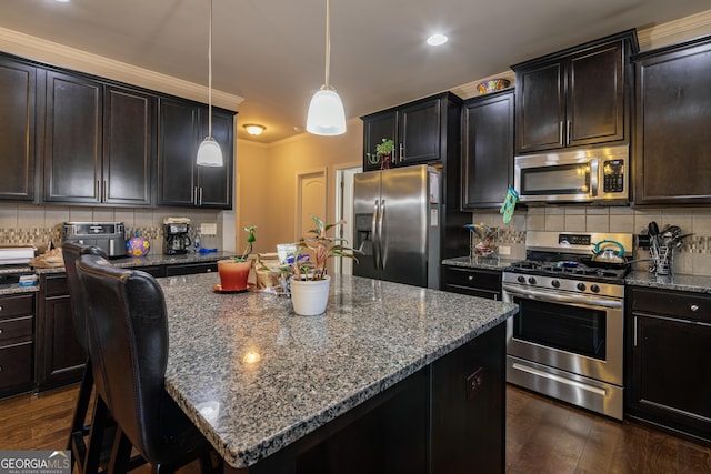 kitchen with appliances with stainless steel finishes, dark brown cabinetry, a kitchen island, and decorative light fixtures