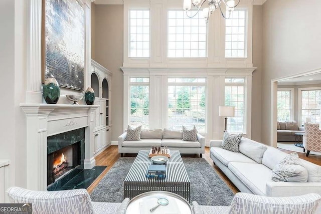 living room with hardwood / wood-style flooring, a chandelier, a towering ceiling, and a fireplace