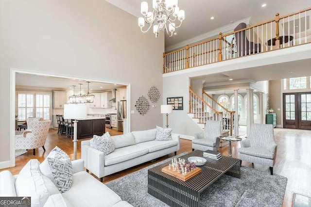 living room featuring an inviting chandelier, hardwood / wood-style floors, ornamental molding, and a high ceiling