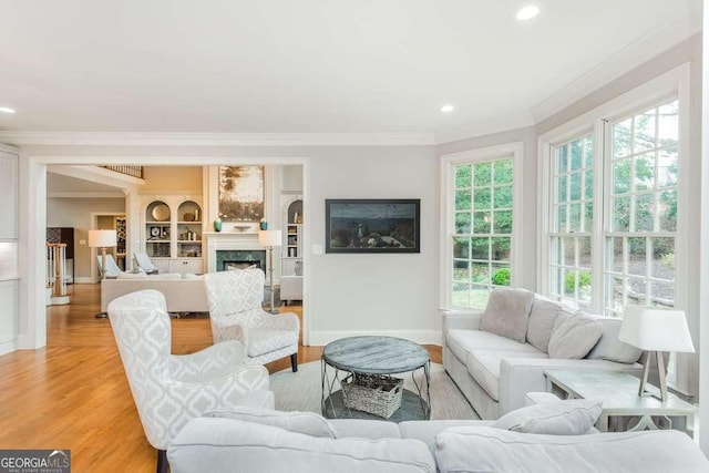 living room with built in features, light hardwood / wood-style flooring, and crown molding