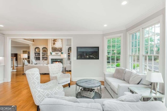 living room with built in features, crown molding, and light hardwood / wood-style floors