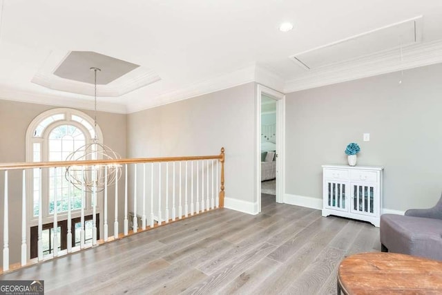 sitting room with light hardwood / wood-style floors, crown molding, and a raised ceiling