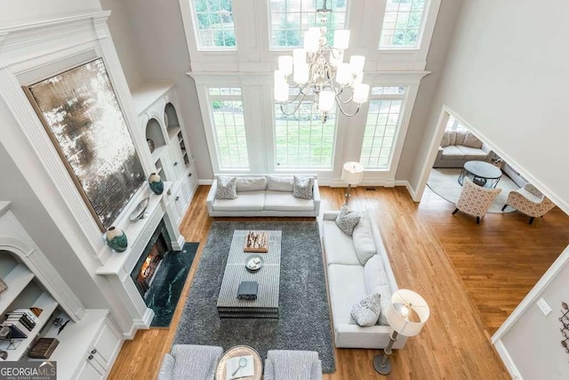 living room featuring a high ceiling, a fireplace, hardwood / wood-style flooring, and a notable chandelier