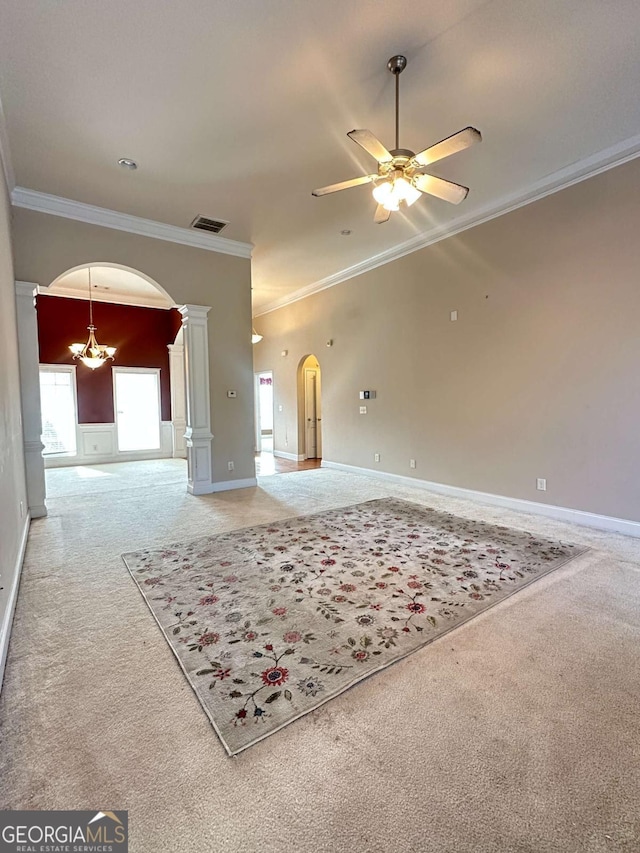 carpeted spare room with ceiling fan with notable chandelier, ornamental molding, and ornate columns