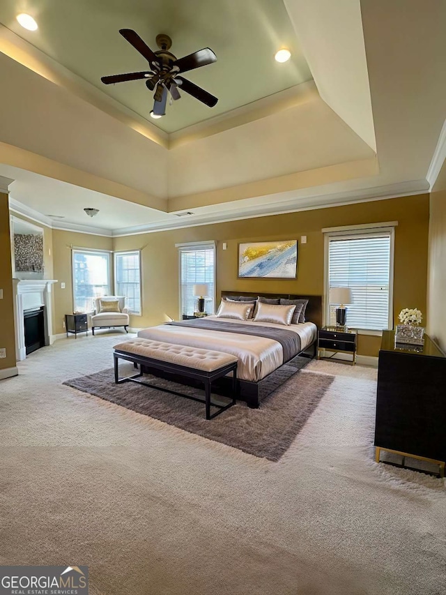 carpeted bedroom featuring a raised ceiling, ceiling fan, and crown molding