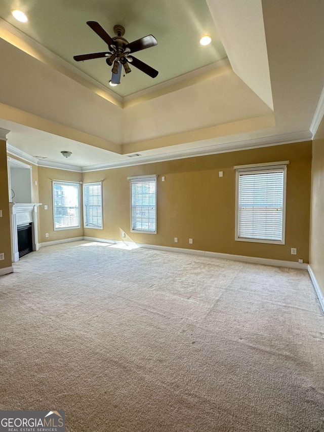 unfurnished living room featuring ceiling fan, crown molding, light colored carpet, and a tray ceiling