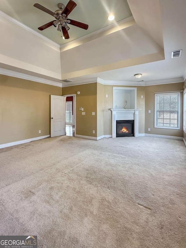 unfurnished living room featuring ceiling fan, carpet, ornamental molding, and a raised ceiling