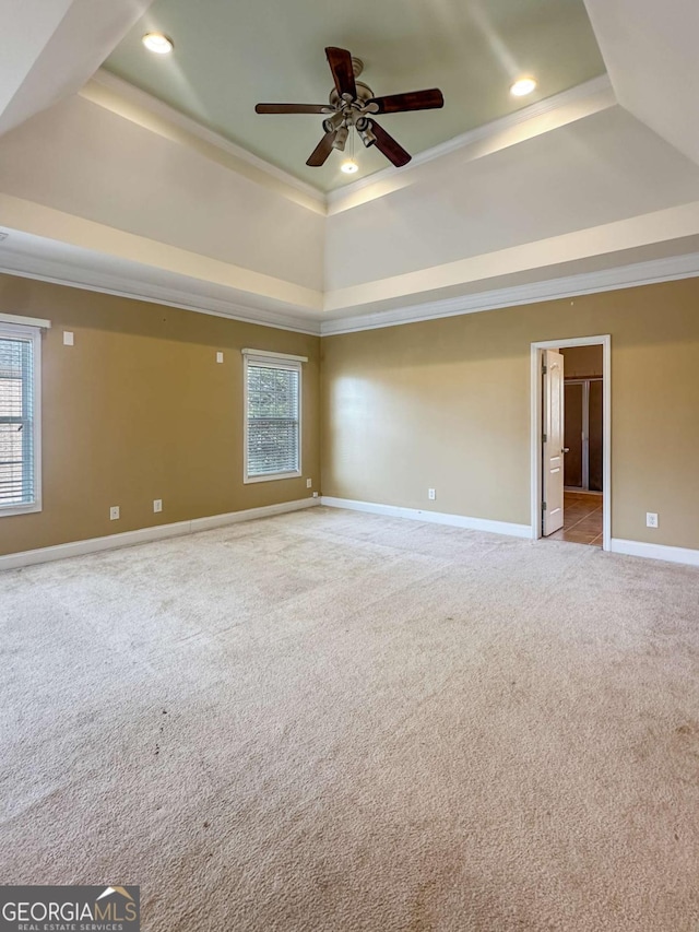 carpeted empty room with a raised ceiling and crown molding