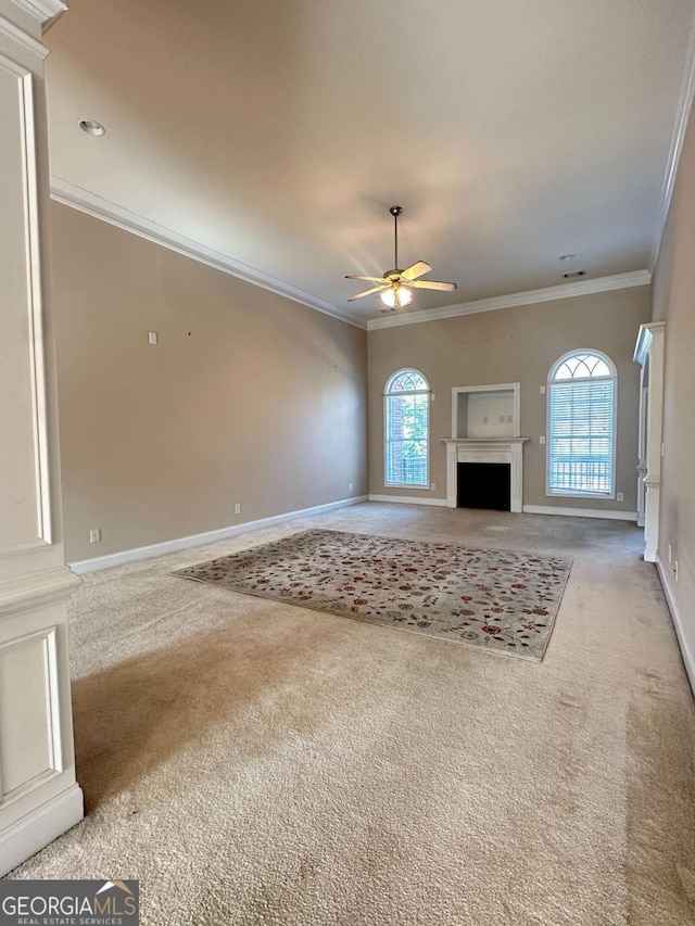 unfurnished living room with ceiling fan, carpet, ornamental molding, and a healthy amount of sunlight