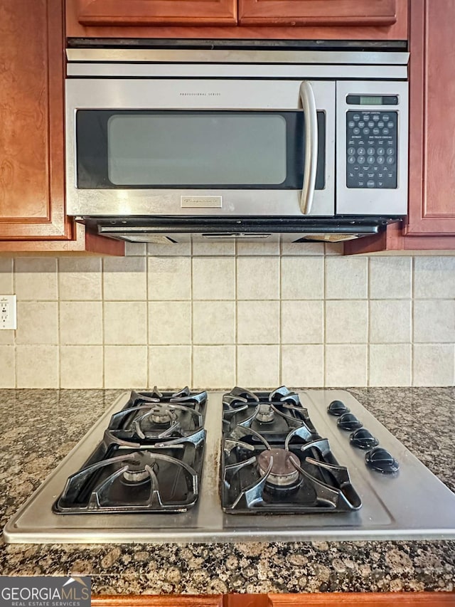 kitchen with tasteful backsplash, gas cooktop, and dark stone counters