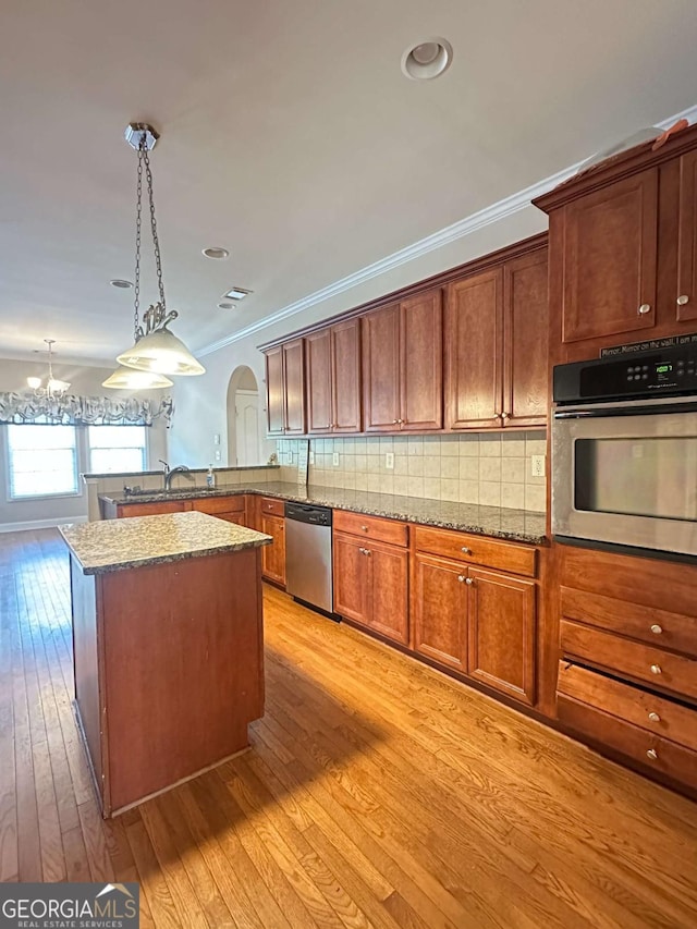 kitchen featuring decorative light fixtures, light hardwood / wood-style floors, decorative backsplash, an inviting chandelier, and appliances with stainless steel finishes