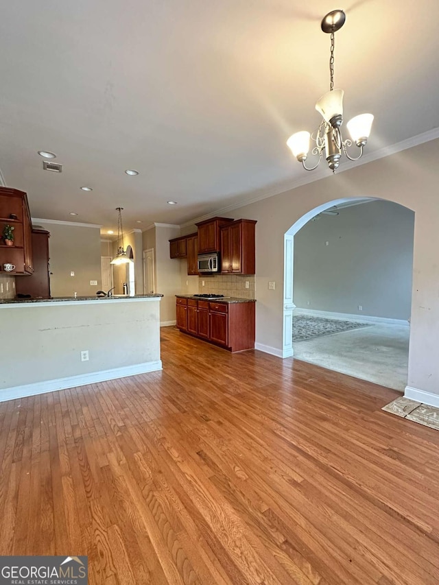 kitchen featuring decorative light fixtures, wood-type flooring, an inviting chandelier, decorative backsplash, and ornamental molding