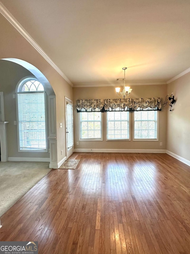 unfurnished dining area featuring ornamental molding, a chandelier, and hardwood / wood-style floors