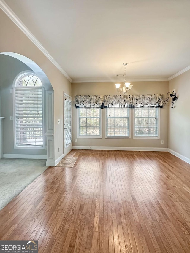 unfurnished dining area featuring hardwood / wood-style flooring, an inviting chandelier, crown molding, and plenty of natural light