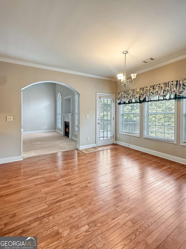 unfurnished living room featuring light hardwood / wood-style flooring, a chandelier, and ornamental molding