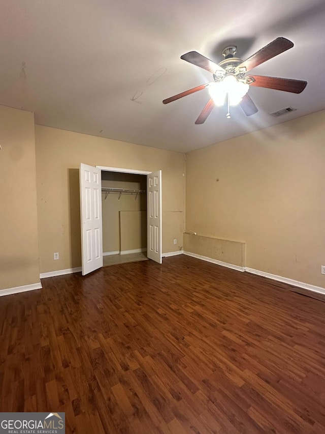 unfurnished bedroom featuring ceiling fan, dark hardwood / wood-style flooring, and a closet