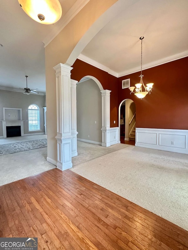 interior space with ornate columns, ornamental molding, ceiling fan with notable chandelier, and light hardwood / wood-style flooring