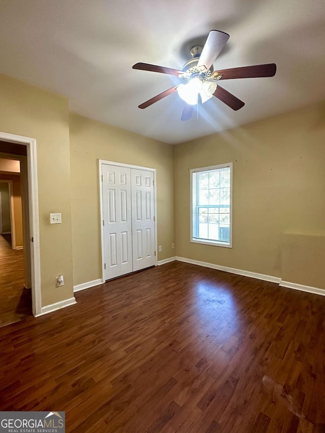 unfurnished bedroom with ceiling fan, dark hardwood / wood-style flooring, and a closet