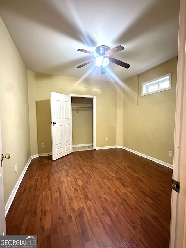 unfurnished bedroom with ceiling fan, dark wood-type flooring, and a closet