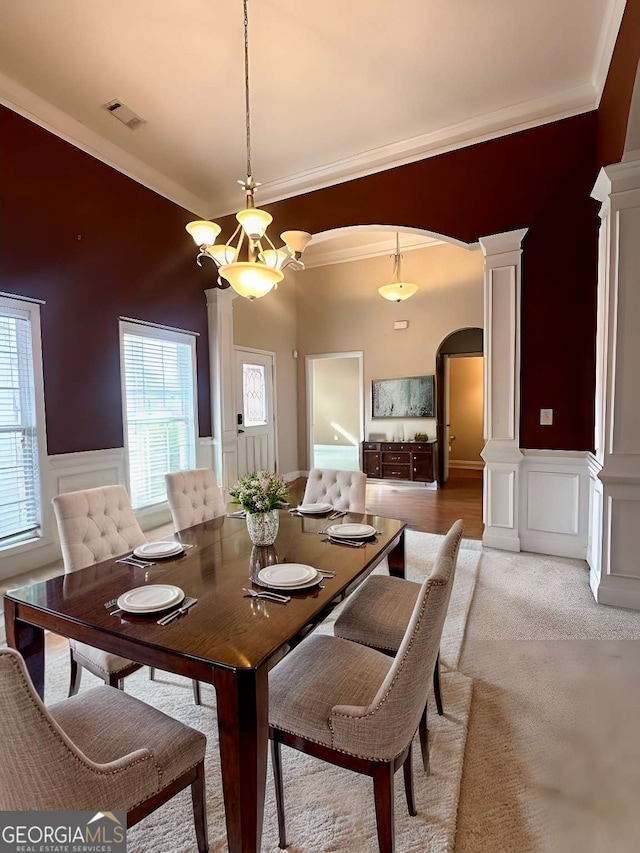 dining room with a notable chandelier, crown molding, and ornate columns