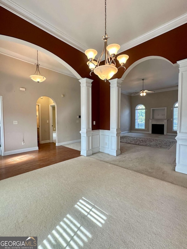 interior space with carpet, ceiling fan with notable chandelier, ornamental molding, and ornate columns