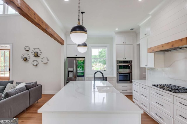 kitchen with hanging light fixtures, a center island with sink, stainless steel appliances, and tasteful backsplash