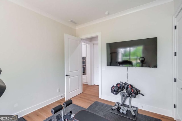 exercise area with hardwood / wood-style floors and ornamental molding