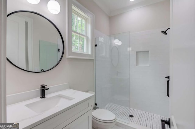 bathroom with crown molding, toilet, vanity, and a tile shower