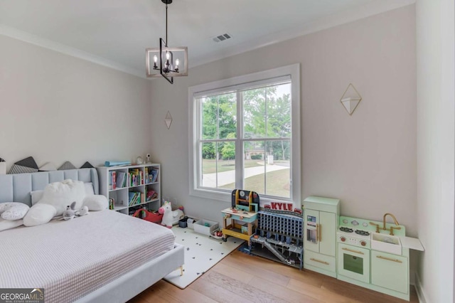 bedroom with an inviting chandelier, crown molding, and hardwood / wood-style floors