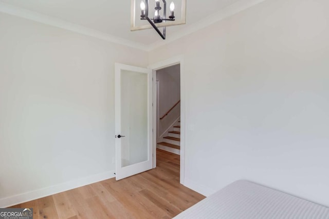 unfurnished bedroom featuring a chandelier, ornamental molding, and light hardwood / wood-style floors