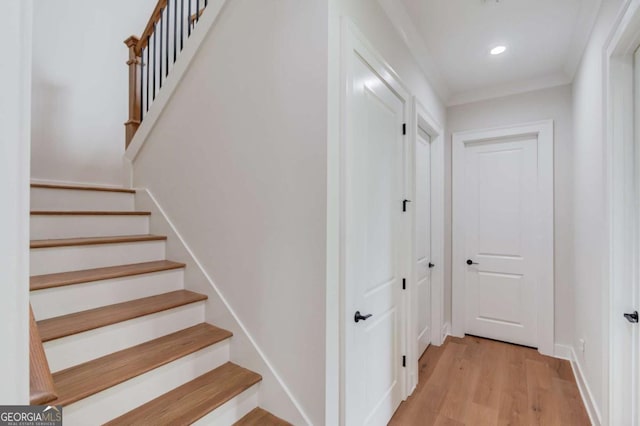 stairs featuring wood-type flooring and ornamental molding