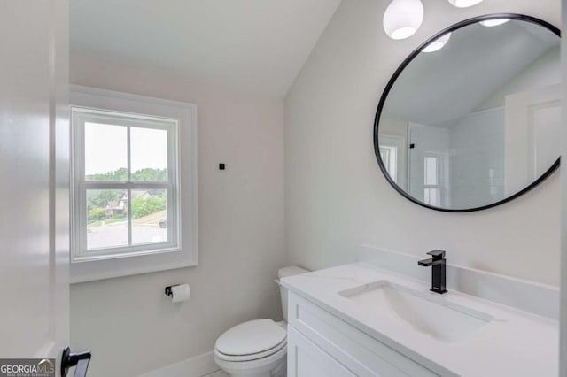 bathroom with toilet, vanity, and vaulted ceiling