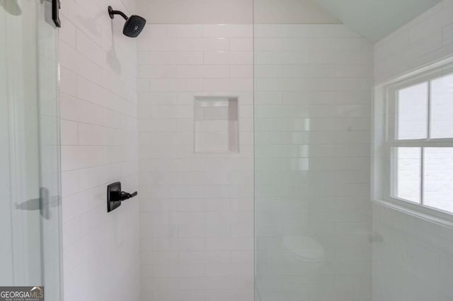 bathroom with lofted ceiling and a tile shower